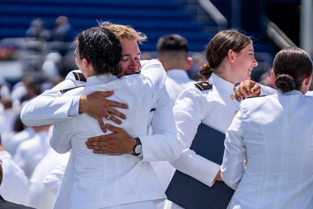 Graduates hug and bid each other farewell after the Naval Academy ceremony ends.