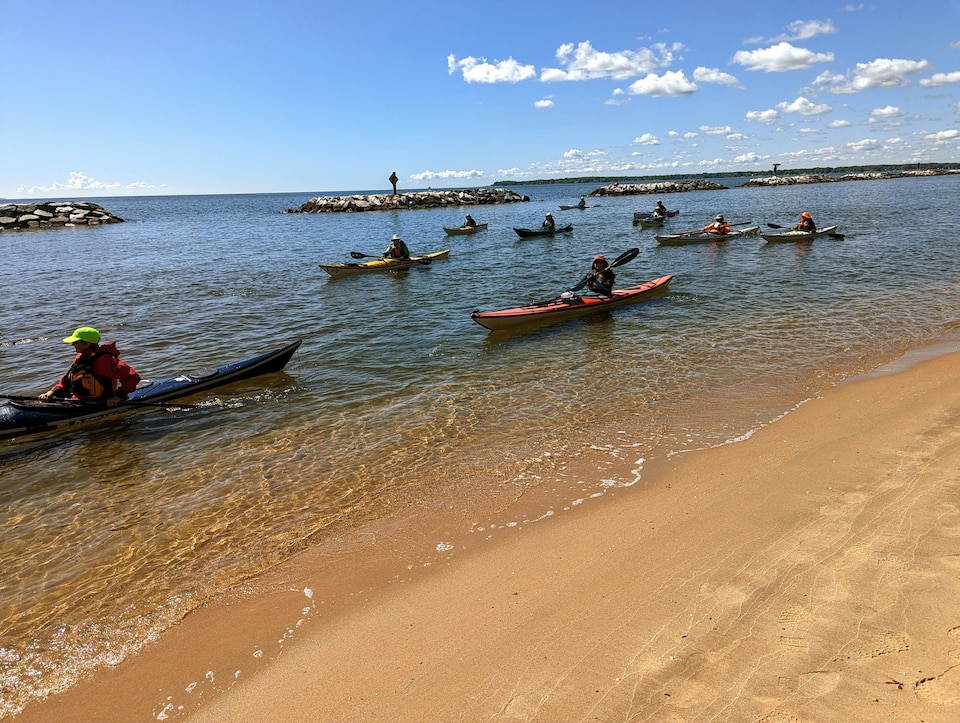 Kayakers paddle along the golden sand beach at Beverly Triton Nature Park just before a dedication ceremony on Friday, May 5. The beach will open for swimming this summer.