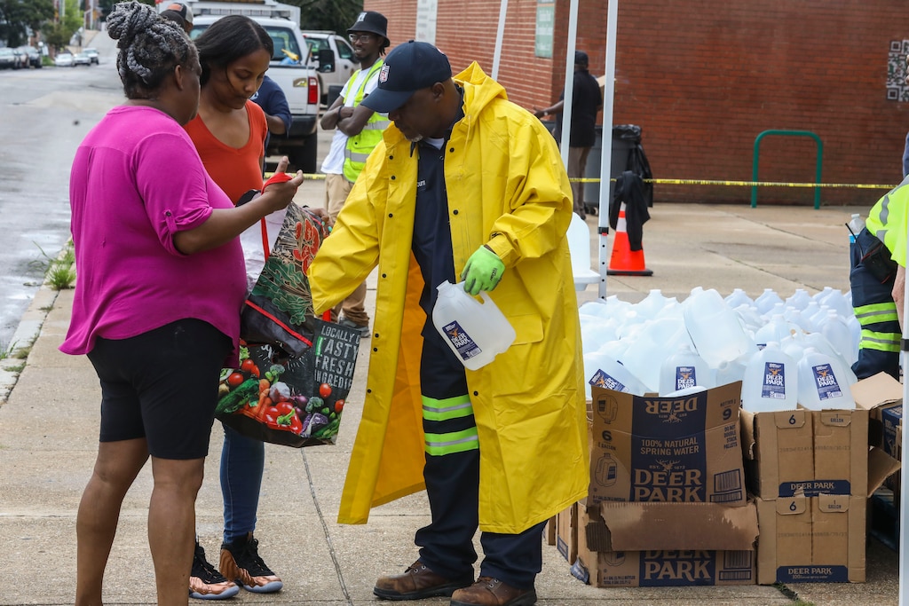 Baltimore Department of Public Works employees hand out water in Harlem Park after the city issued a boil advisory. Baltimore’s public works department first noted E. coli and coliform through routine testing on Friday.