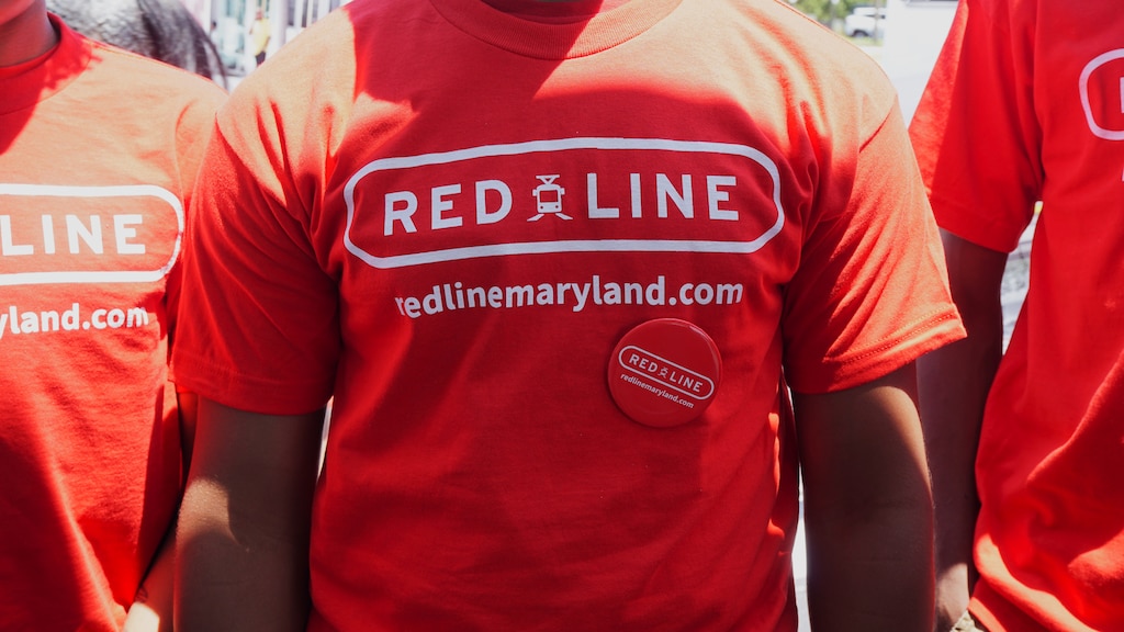 A close up image of three people wearing red t-shirts that say "RED LINE" and "redlinemaryland.com"