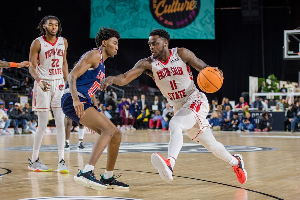 This photo shows Jonathan Hicklin of Winston-Salem State dribbling the ball and running toward Lincoln's Bakir Cleveland in the men's championship game of the CIAA basketball tournament at CFG Arena.