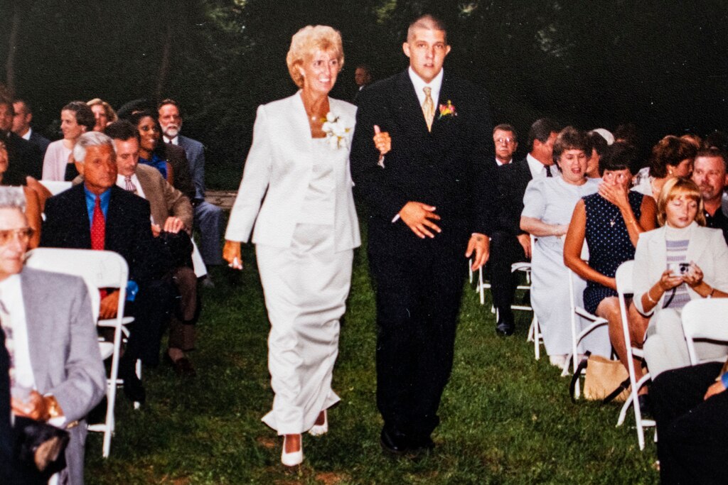 A picture showing Mona Setherley walking her son Bruce Setherley down the aisle during a wedding.