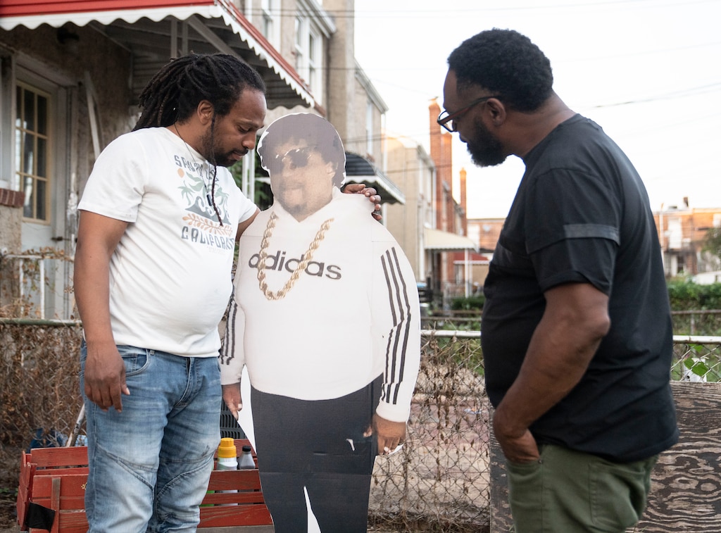 Michael Brooks and Steve Diggs share a moment with the cardboard cutout of Al Holden during a birthday memorial honoring Holden in Baltimore on September 21, 2023. Al Holden passed away from an overdose on his 50th birthday in 2020.