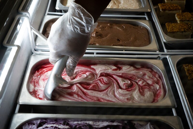Cajou Creamery co-founder Dwight Campbell scoops raspberry cheesecake ice cream.