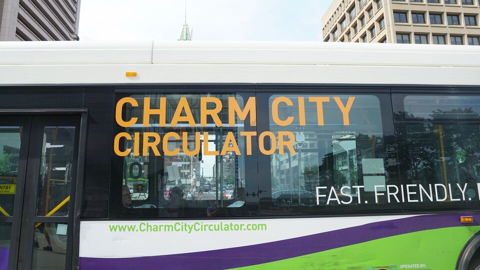 The side of a bus is shown. Words on it say "CHARM CITY CIRCULATOR" and "FAST. FRIENDLY."