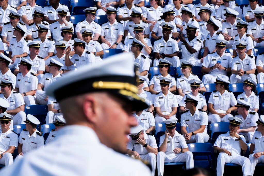 Midshipman clap and cheer as they watch their friends walk down the stairs to their seats before the ceremony begins.
